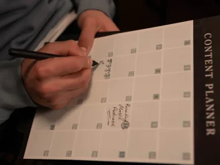 hand planning a content calendar on a printed planner