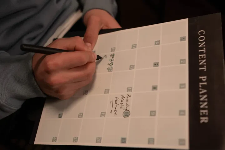 hand planning a content calendar on a printed planner