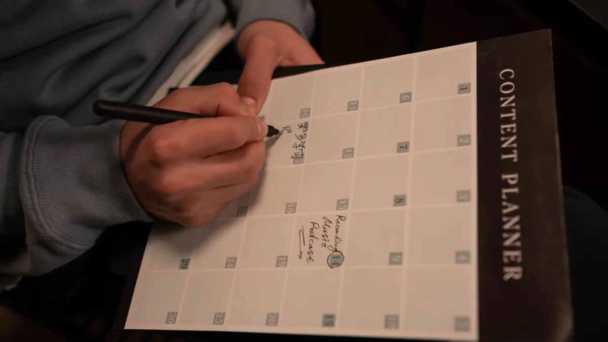 hand planning a content calendar on a printed planner