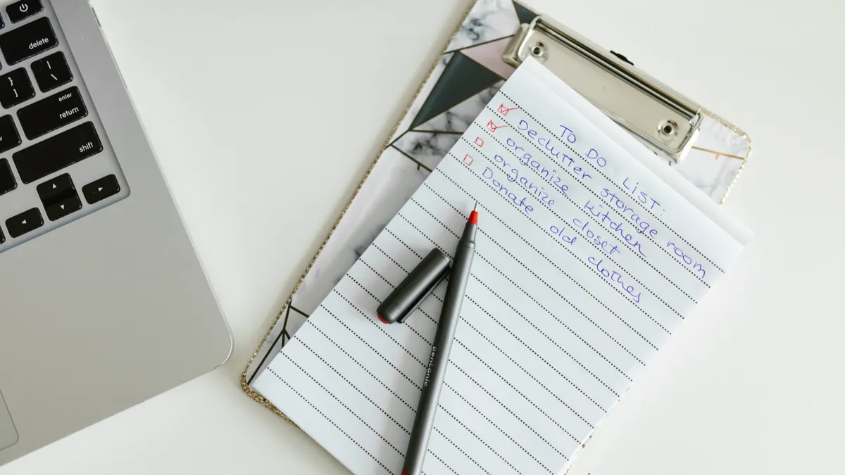 clipboard with notes beside a laptop