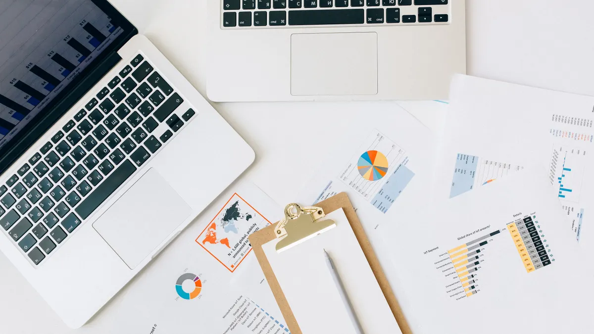 desk with laptop, clipboard, and analytics charts