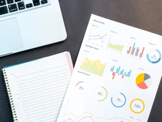 laptop beside notebook and printed charts