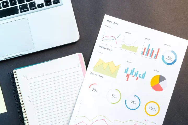 laptop beside notebook and printed charts