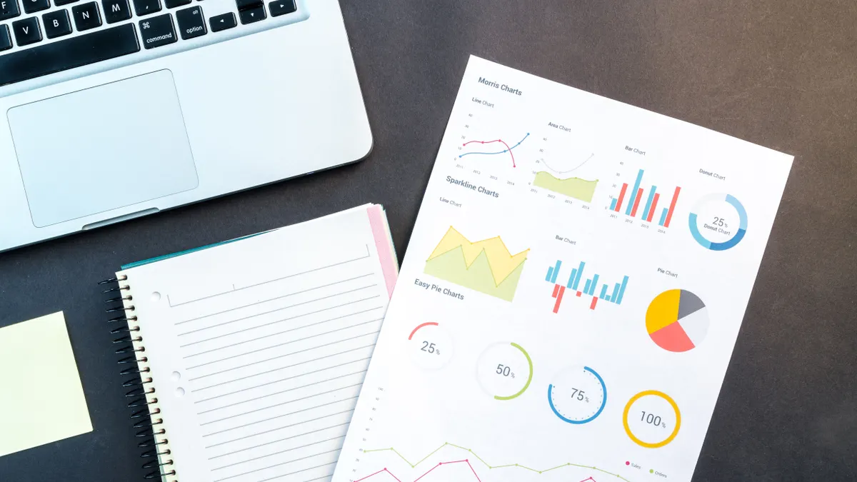laptop beside notebook and printed charts