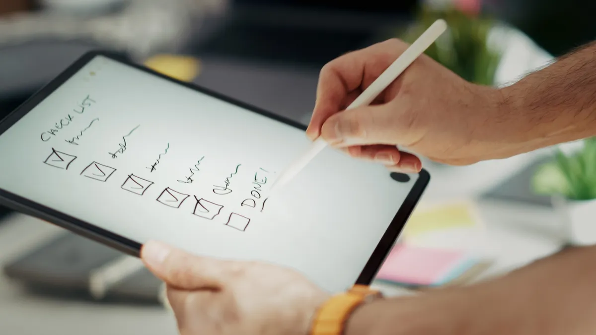 Hand marking a checklist on a tablet