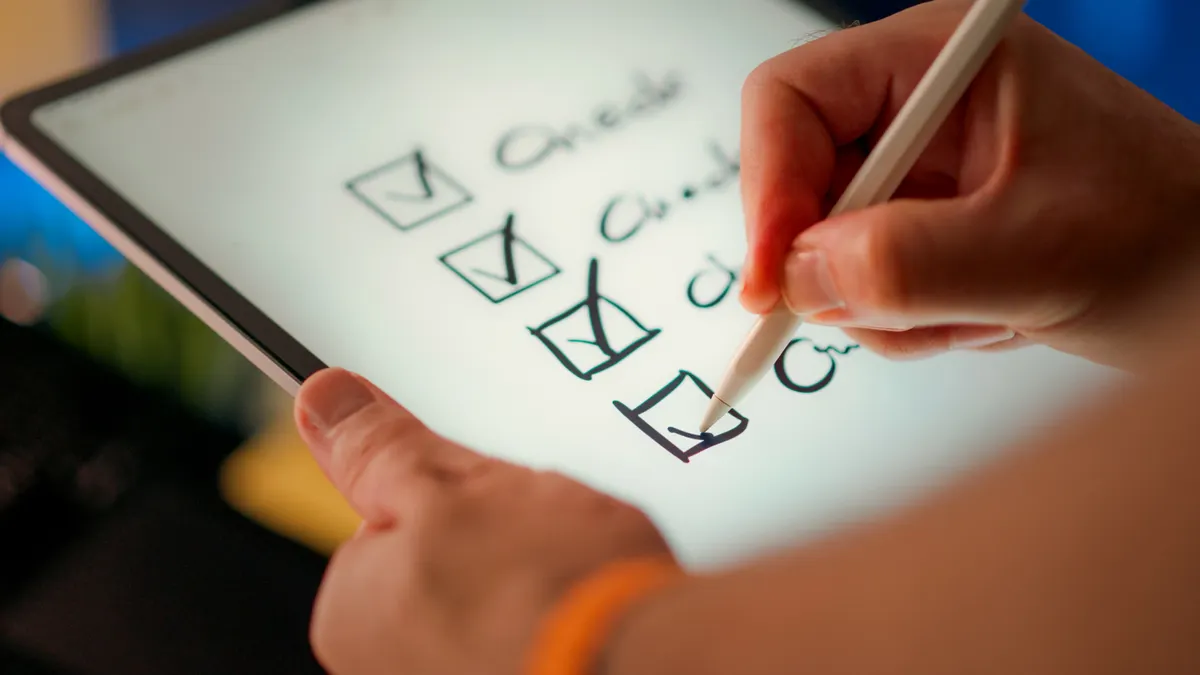 Hand checking boxes on a tablet screen