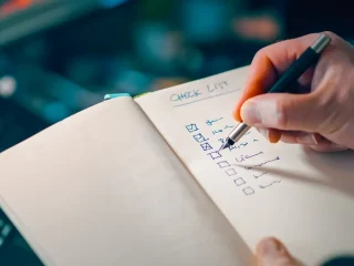 Hand ticking items on a checklist notebook