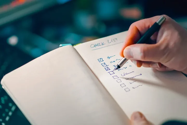 Hand ticking items on a checklist notebook