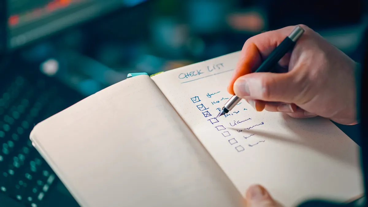 Hand ticking items on a checklist notebook