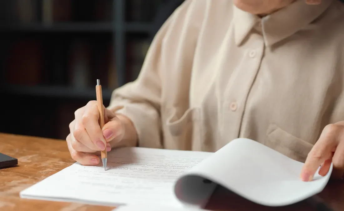 person proofreading a printed document at a desk