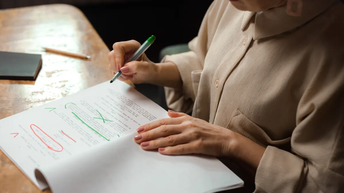 person marking up a printed draft with pen