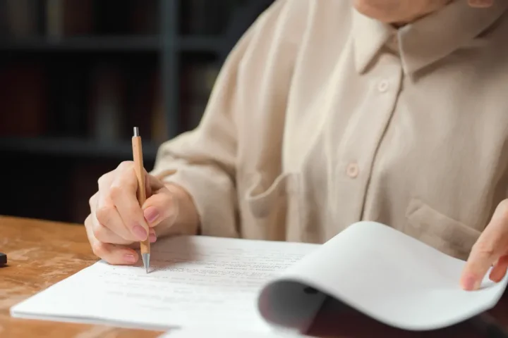 person proofreading a printed document at a desk