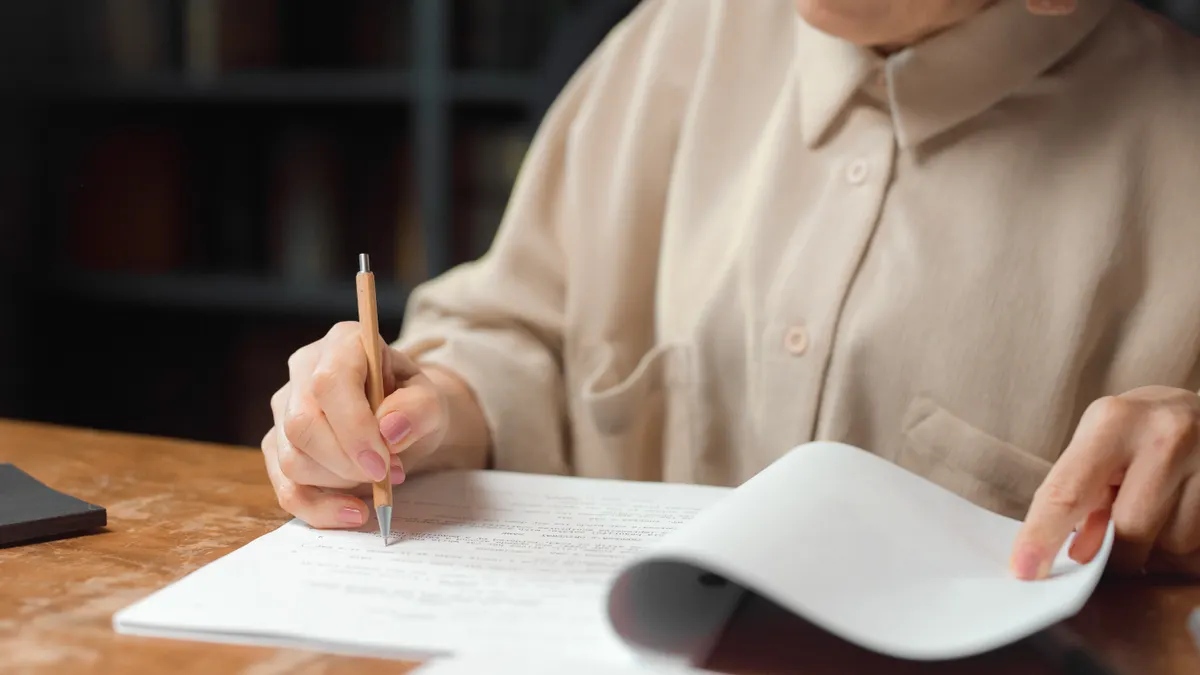 person proofreading a printed document at a desk